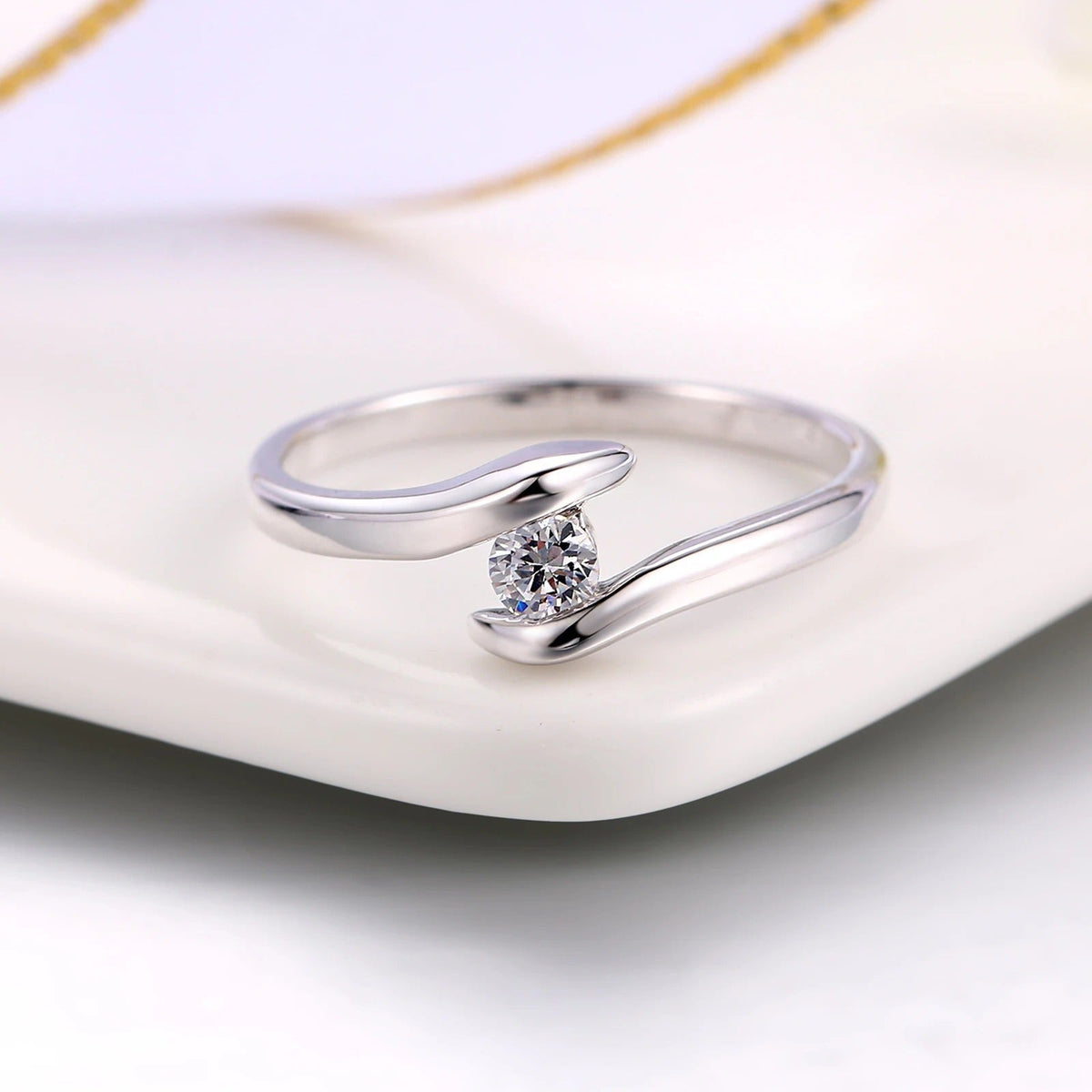 Ring met gebogen staaf en stralende diamant in het midden in wit goud